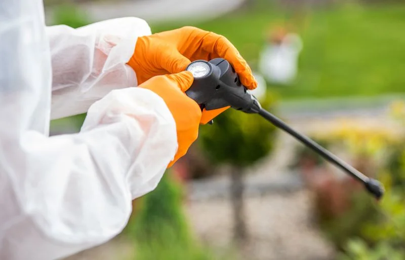 A professional with gloves checking the meter on a pesticide sprayer hose