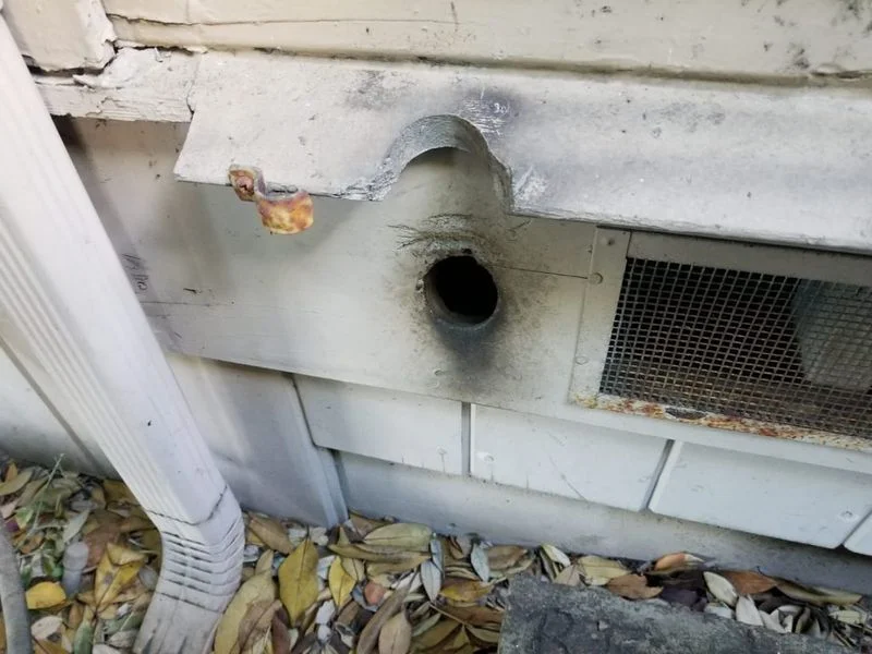A large, perfectly round hole in the side of a house wall