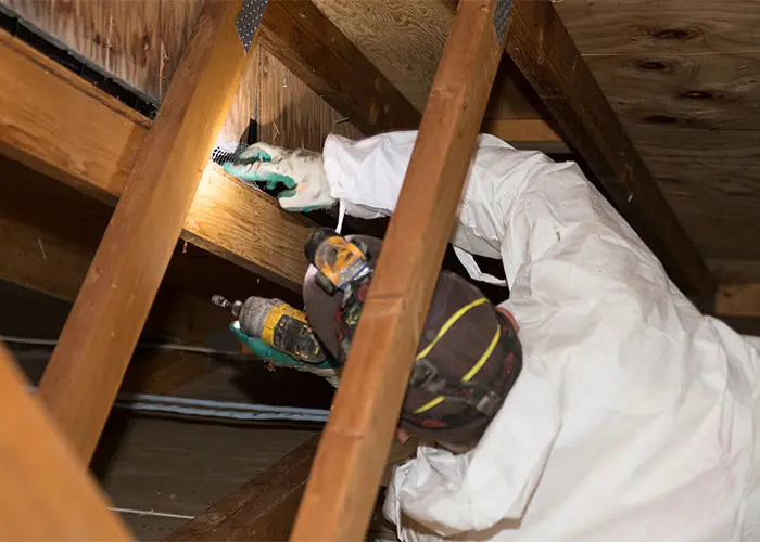 A man inspecting the underside of a home