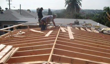 Two men repairing a deck roof made of wood