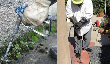 A man spraying pesticide along the bottom of an outdoor wall