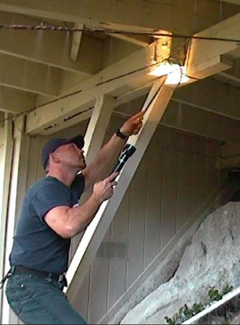 A man in baseball cap examining a wooden beam for termites