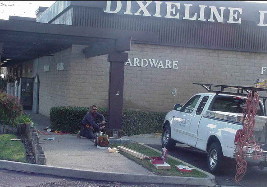 A man working with pesticides and gloves outside a hardware store