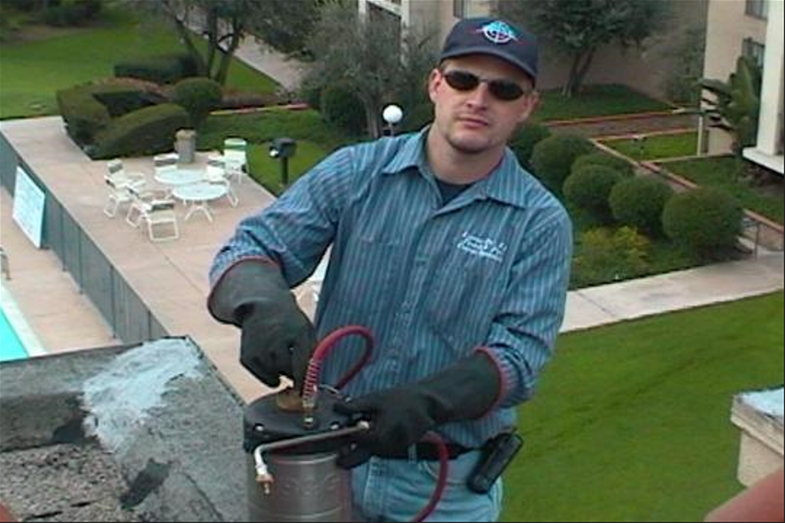 Shawn with sunglasses, hat, and gloves preparing a pesticide cannister